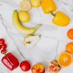 Vibrant top view of assorted fruits and vegetables arranged in a circle on a marble surface.