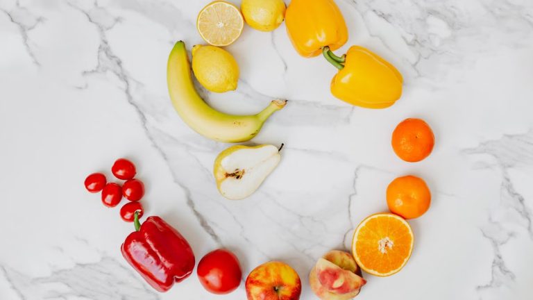 Vibrant top view of assorted fruits and vegetables arranged in a circle on a marble surface.