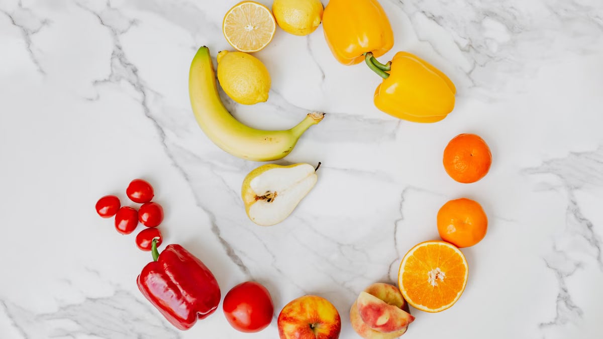 Vibrant top view of assorted fruits and vegetables arranged in a circle on a marble surface.
