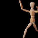 Wooden mannequin artfully posed against a black backdrop, showcasing movement.